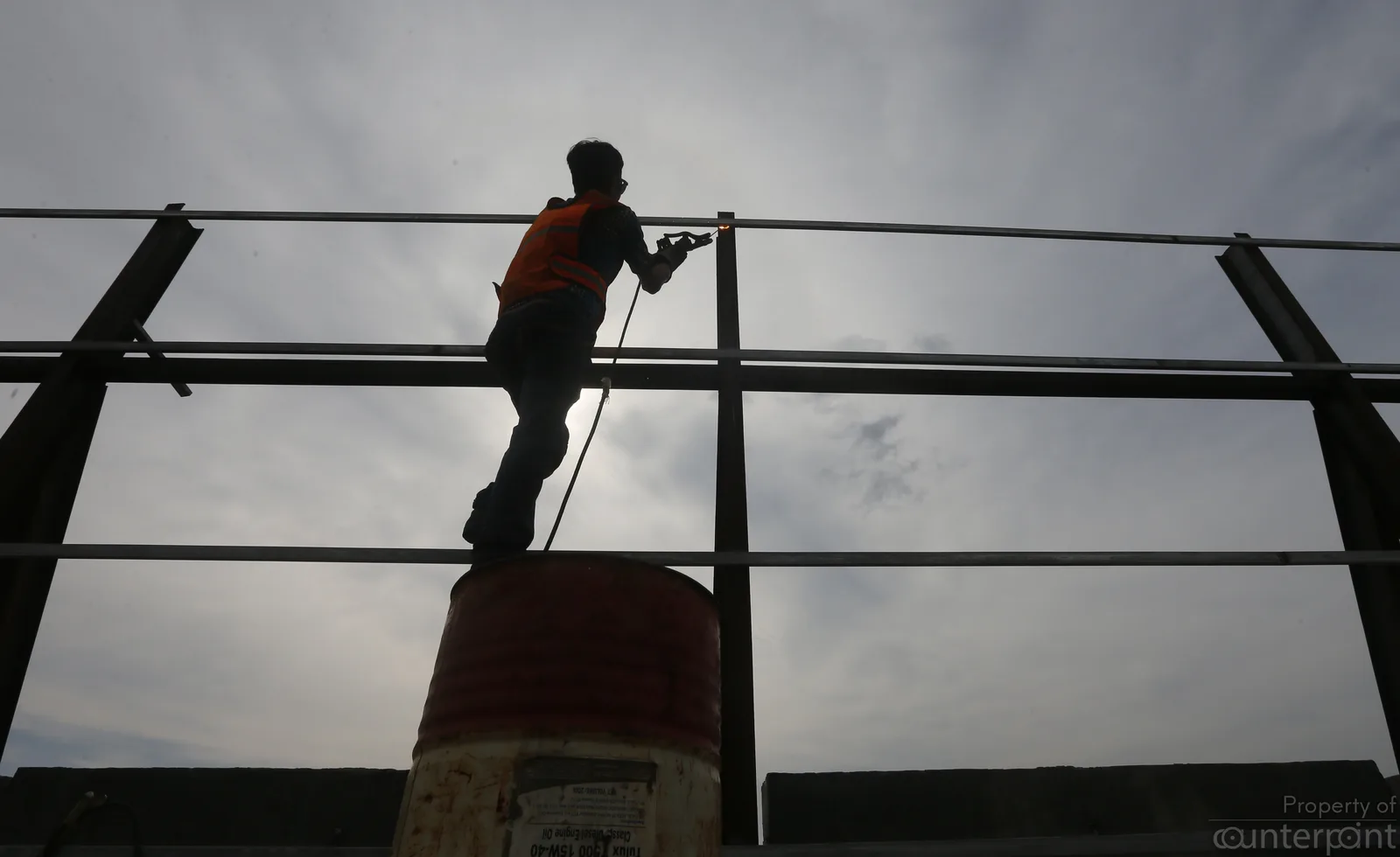A welder hard at work as he balances on a barrel during the construction of the Colombo Port City in 2017.