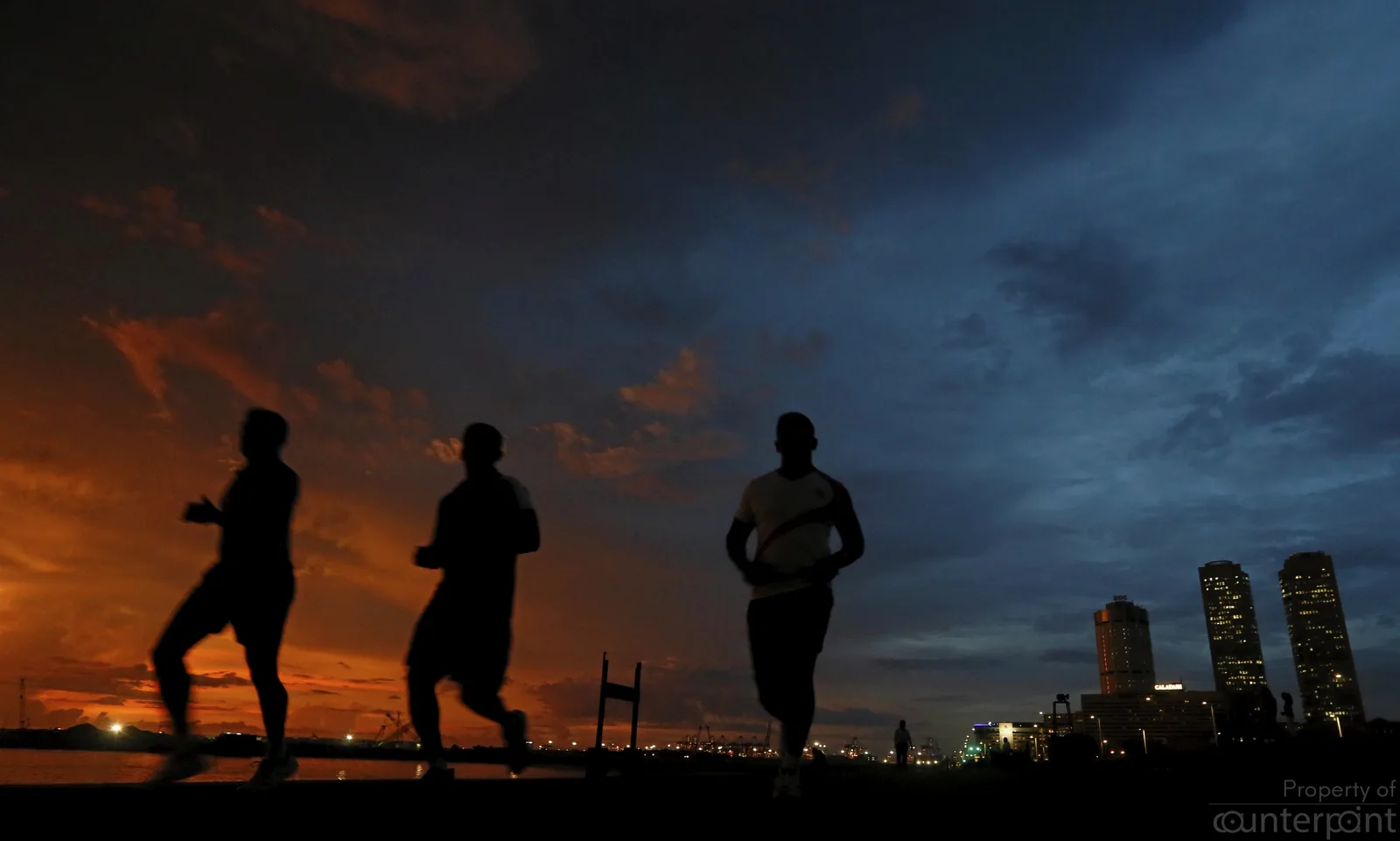 The rising Colombo Port City is seen in the background as people jog on the Galle Face Green in 2017
