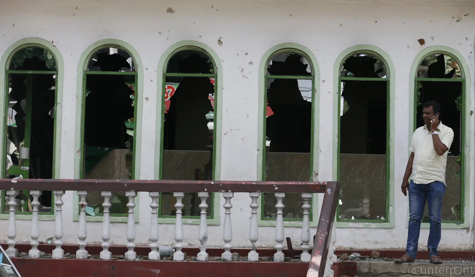 Aftermath of a riot. A man on the phone in front of a destroyed mosque in Kandy on 08, March. 